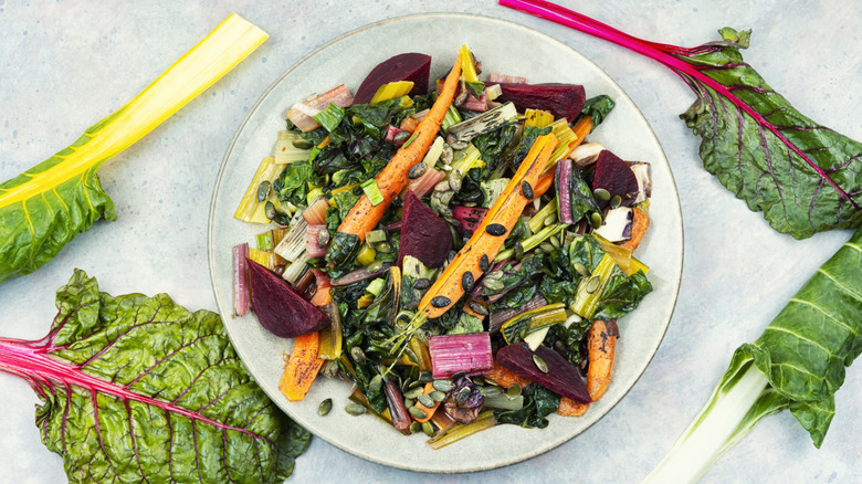 A plate of roasted vegetable salad on a marble table with salad greens