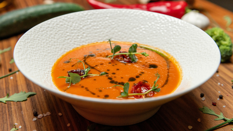 Roasted tomato and vegetable soup in a white bowl placed on a wooden table