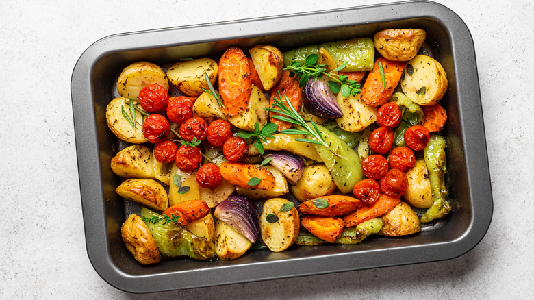 A baking dish full of assorted roasted vegetables on a white table