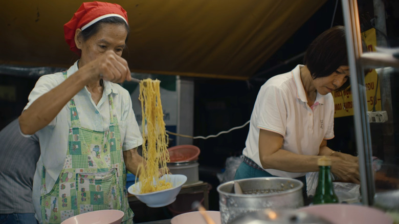 Street food vendors prepare food in Street Food: Asia
