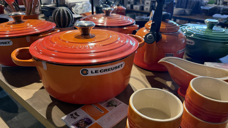 A selection of Le Creuset cookware, including Dutch ovens, kettles, and ramekins, are seen displayed in a store