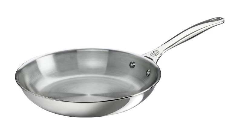 A Le Creuset Stainless Steel Fry Pan, seen on a white background