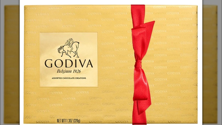 A golden box of Godiva chocolates with a red ribbon bow