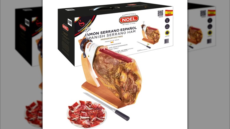 A whole leg of Spanish cured serrano ham, with stand and carving board, as well as a knife