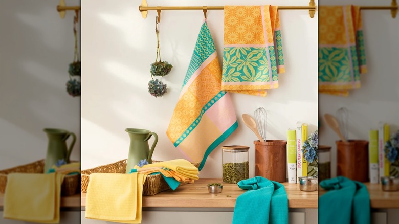 Large kitchen towels in an orange, pink, and green color scheme arranged in a kitchen