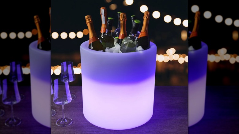 A beverage tub lit purple and holding 8 bottles of wine and champagne plus ice