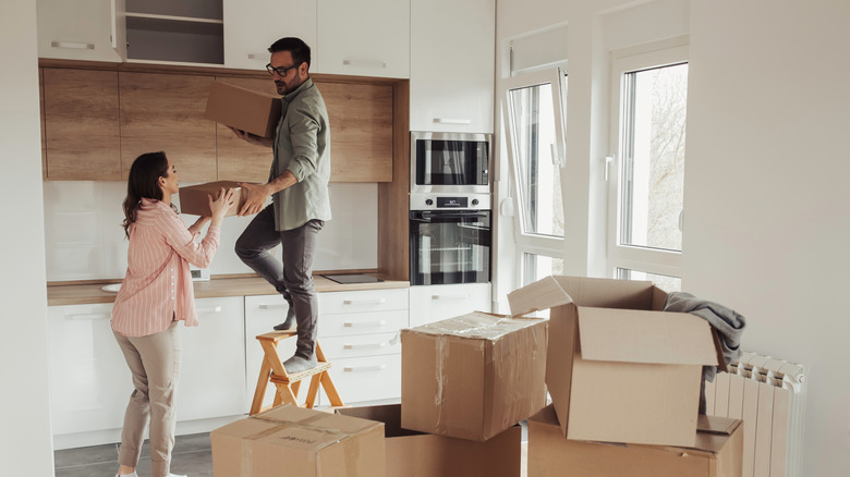 Man and woman in kitchen, unpacking boxes