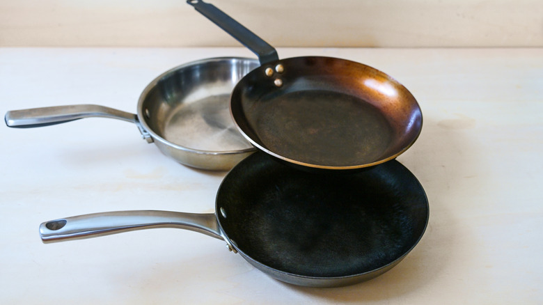 Three frying pans grouped together on beige surface