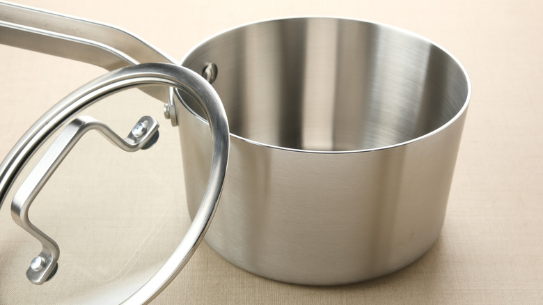 Stainless steel saucepan with lid resting on edge