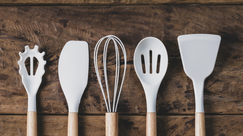 Set of white and wood cooking utensils on wood surface