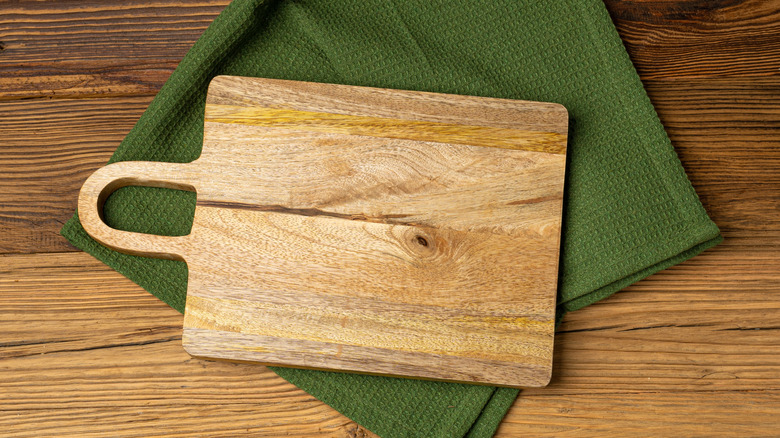 Wood cutting board on green kitchen towel