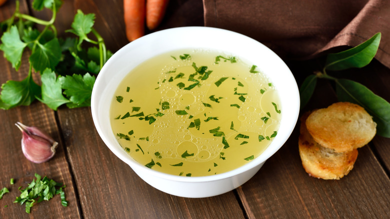 Chicken broth in bowl, surrounded by ingredients