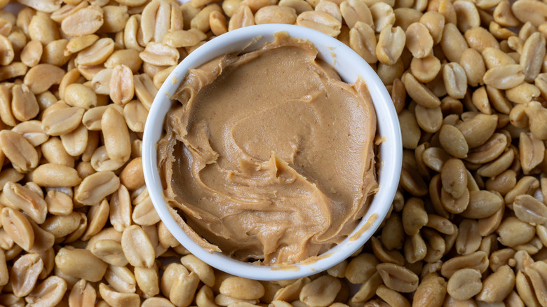 A bowl of peanut butter on some peanuts