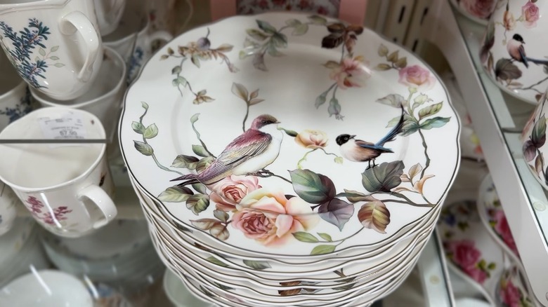 Stack of white plates with bird print on HomeGoods shelf.