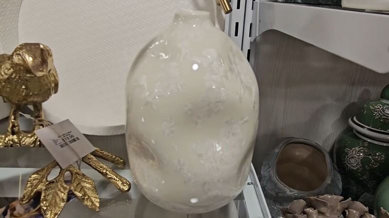 Shiny white vase with dimples and a narrow neck on HomeGoods shelf.