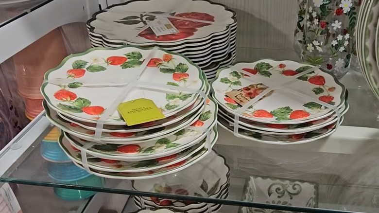 White plates with tomato and strawberry patterns stacked on HomeGoods shelf.