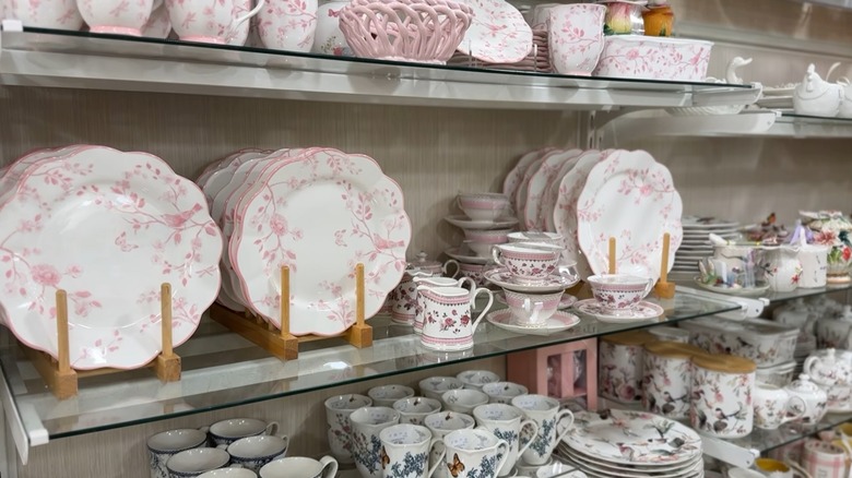 Plates and mugs with decorative pink details on HomeGoods shelf.