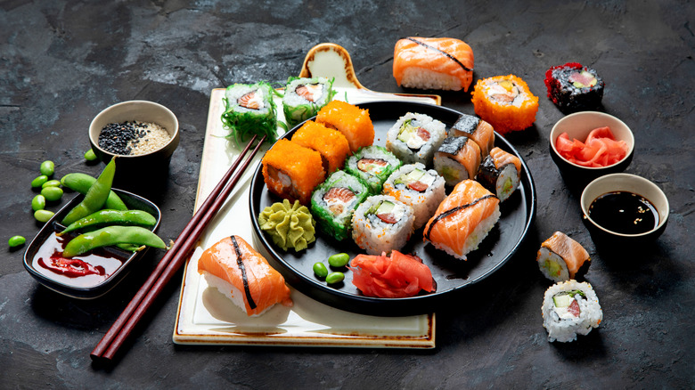 An assortment of colorful sushi, edamame beans, and various condiments