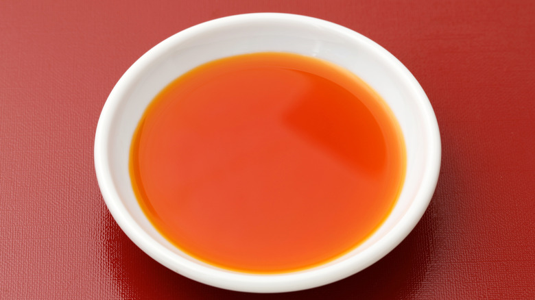 A small bowl of chili oil on a red background