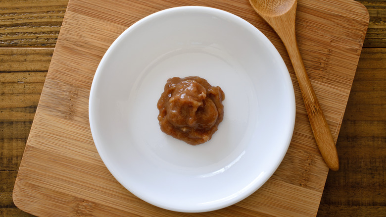 An overhead view of a bowl of umeboshi paste, sitting on a wooden board