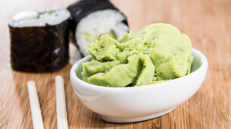 A small bowl of wasabi is pictured, with maki rolls in the backround