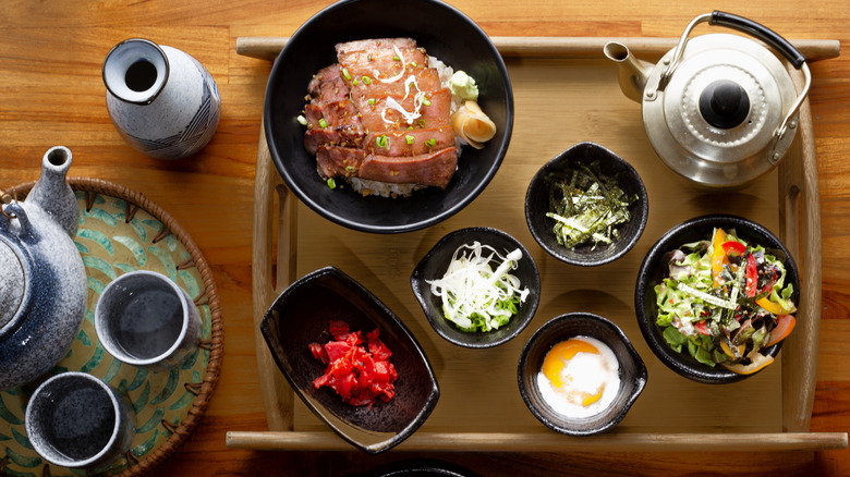 Japanese grilled beef donburi lunch set with side dishes on a wooden tray