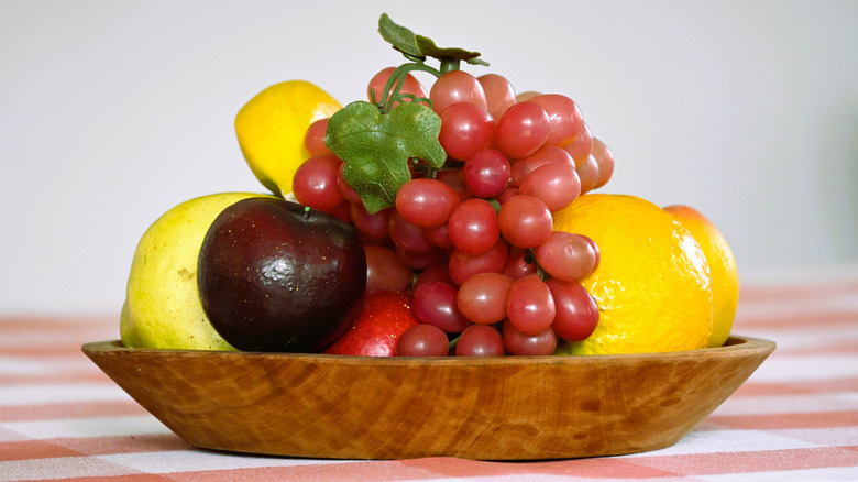 A wooden bowl of artificial fruit