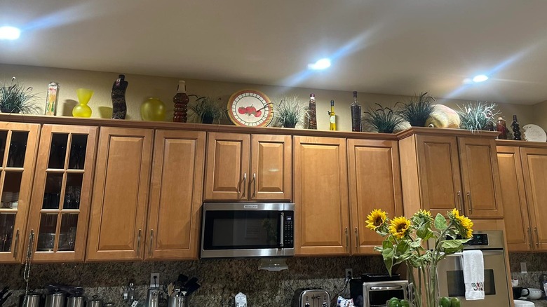 A lot of items displayed and stored in the space between the upper kitchen cabinets and ceiling