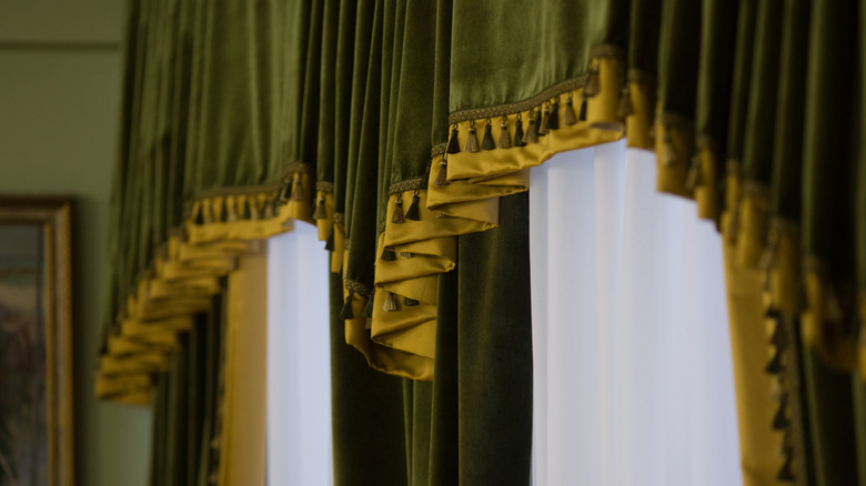 Heavy, green ruffled curtains dressed on a window