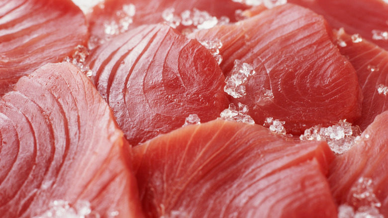 Rows of piled, pink frozen tuna on ice.