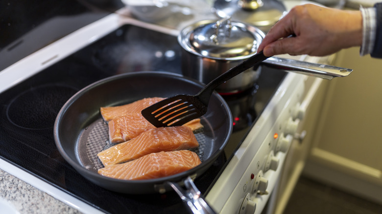 Salmon filets being cooked in a frying pan.