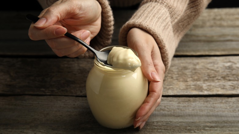 Person holding mayo jar with spoonful of mayo