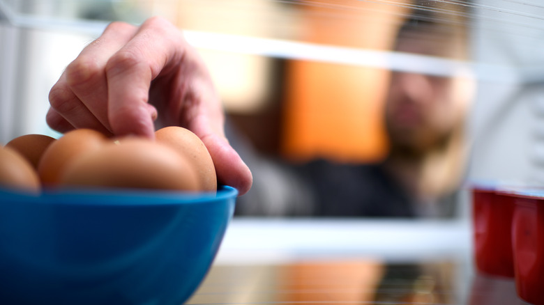 person grabbing eggs from fridge