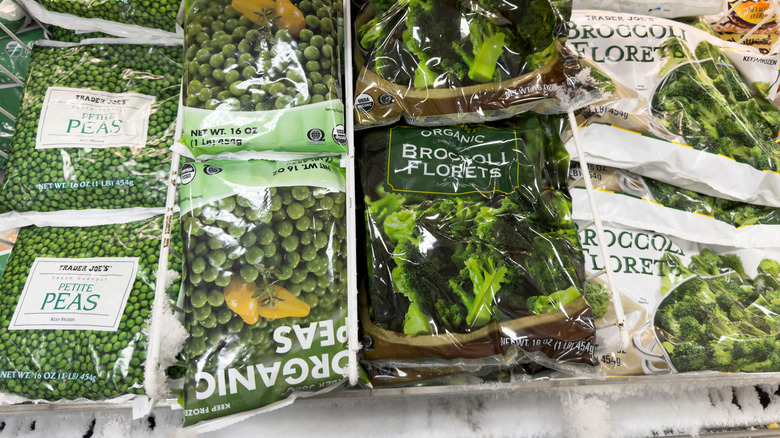 An overhead view of bags of peas and broccoli florets in a Trader Joe's freezer.