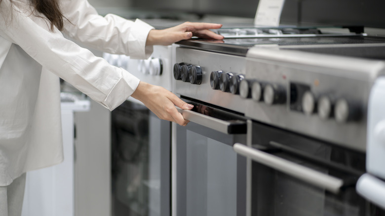 Shopper reaching to open the oven on a range