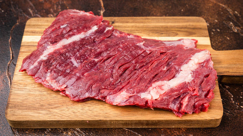 A raw piece of bavette steak laid on a wooden cutting board
