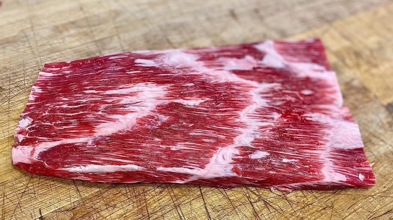 A raw toro steak on a wooden cutting board