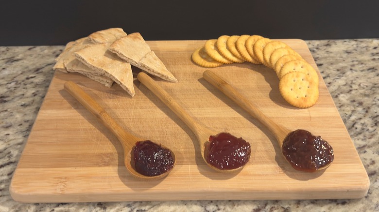 Cutting board with crackers, pita & wooden spoons of jam