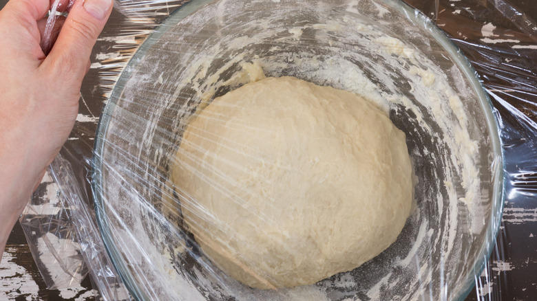 Covering dough with plastic wrap