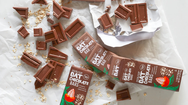 Broken up oat chocolate bars on wrapping with the brown product packages nearby.