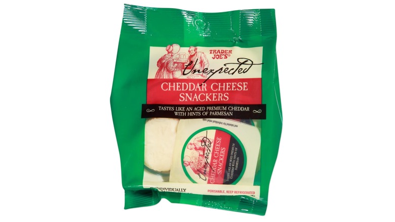 A green bag of Trader Joe's Unexpected Cheddar Cheese Snackers against a white background.