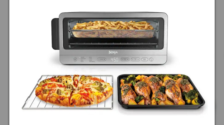Ninja Flip Toaster Oven & Air Fryer on a white background, next to a pizza and dish of chicken