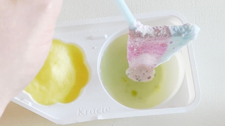 Gummy tsureta candy demonstration, hand pulls straw out of plastic tray with liquid to create a gummy candy