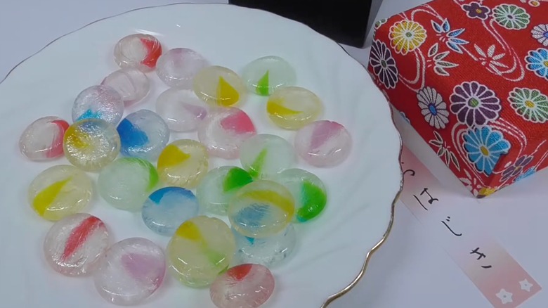 Colorful Ohajiki hard candies on plate next to decorative floral gift box that they come in
