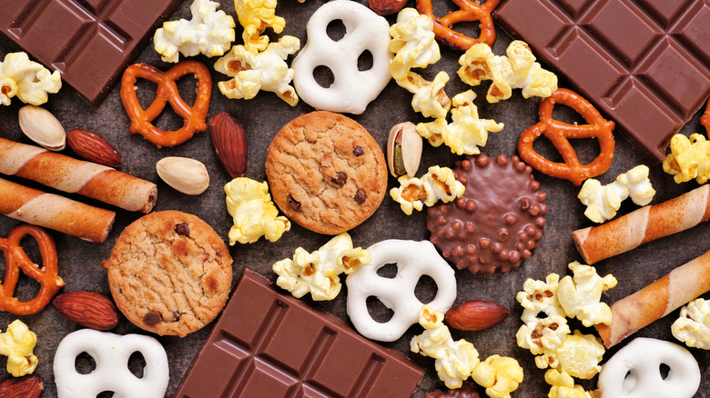 An aerial view of popcorn with chocolate bars and other treats on a slate colored table top.