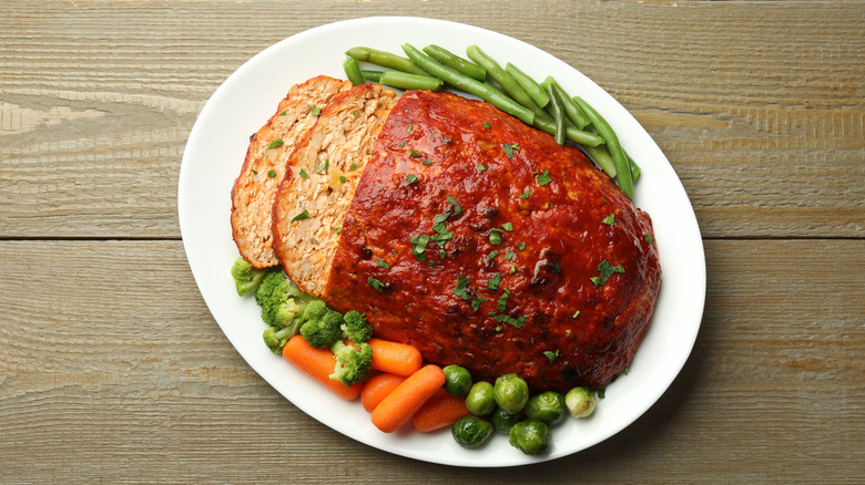 Overhead view of a meatloaf, with boiled vegetables