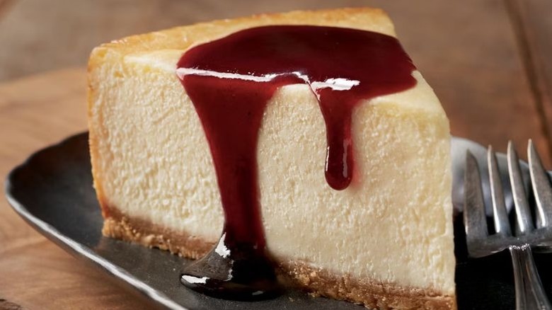 A slice of cheesecake with red sauce served on a plate at Outback Steakhouse