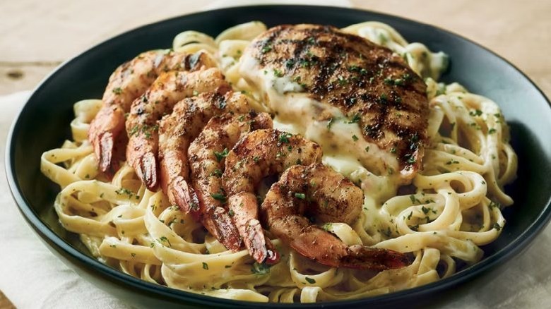 A pasta with shrimp and chicken served on a fettuccine alfredo.