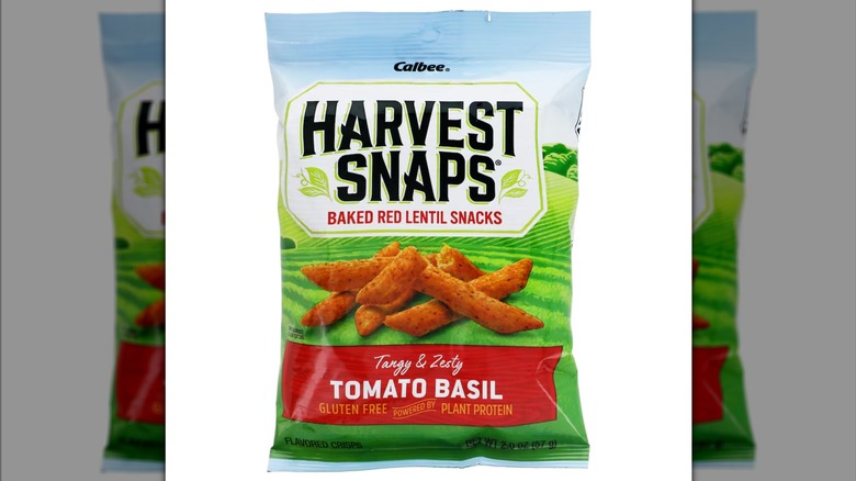 A bag of Harvest Snaps Red Lentil Vegetable Snack Crisps against a white background.