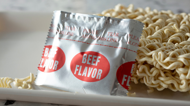 Sachet of beef flavored instant ramen seasoning leaning against an instant ramen nest